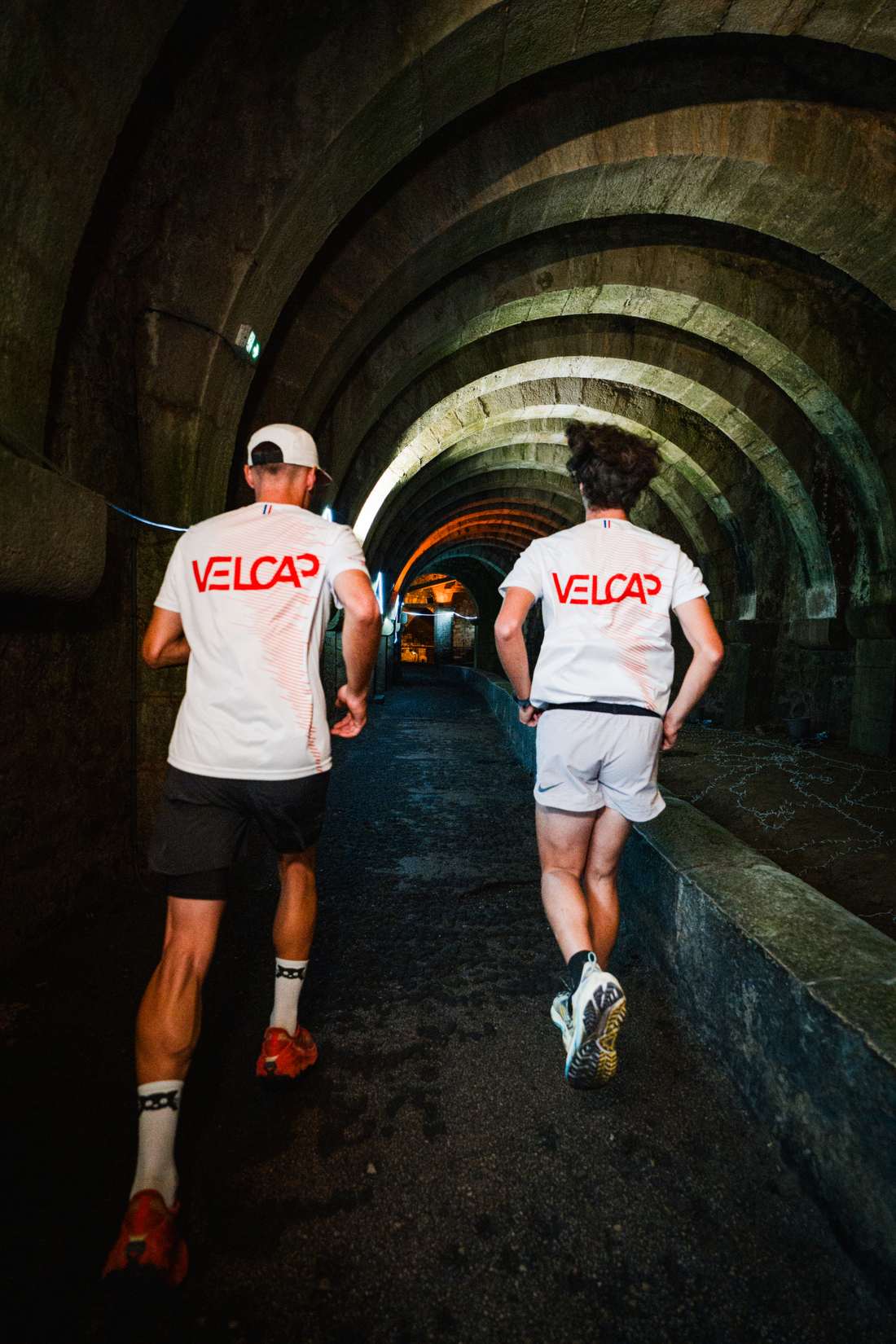 Deux coureurs de dos dans la galerie voûtée